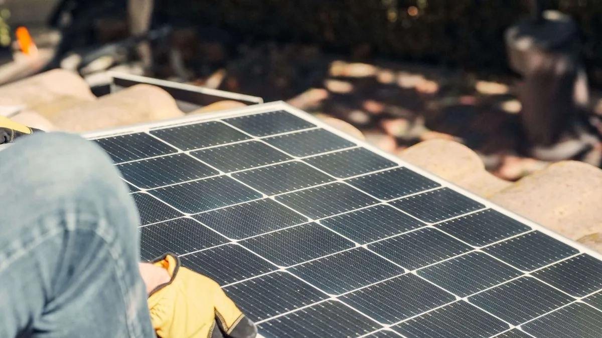 Person trägt ein Solarmodul zur Installation